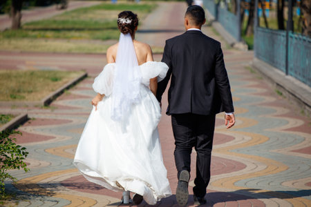 The bride in a wedding dress and the groom are walking in the park. Detailed photo.の写真素材