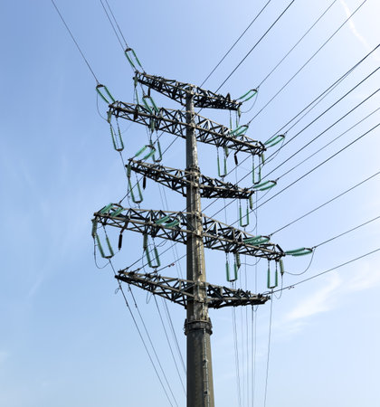 A pole with electric wires against a blue sky.