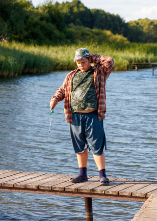 A boy is fishing with a small fishing rod on a pond.の写真素材