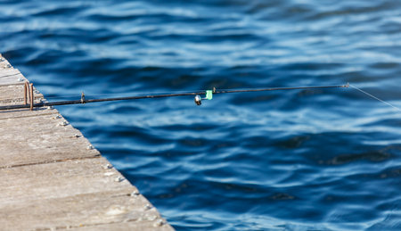 A fisherman's fishing rod on a wooden bridge on a lake.の写真素材