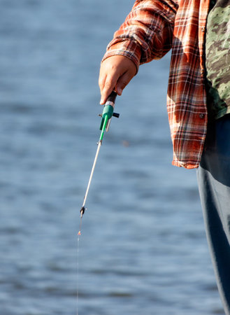 A boy is fishing with a small fishing rod on a pond.の写真素材