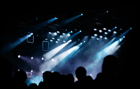 Silhouettes of spectators against a background of blue light at a concert.の写真素材