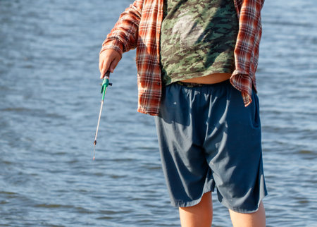 A boy is fishing with a small fishing rod on a pond.の写真素材