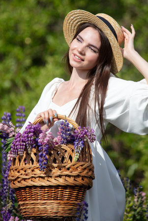 Girl with a hat and a basket in lupine flowers.の写真素材