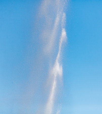 Water splashes from a fountain against a blue sky.の写真素材
