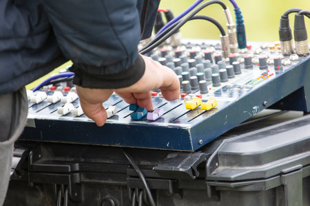 A man is adjusting the knobs on a sound board. Scene is focused and determinedの写真素材