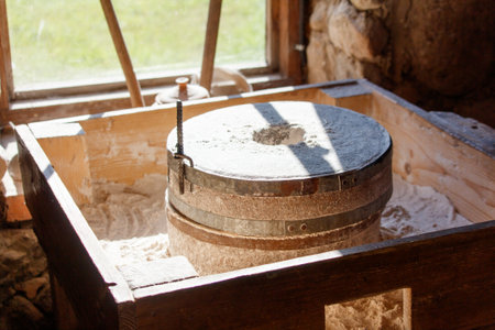 A wooden box with a large grinding stone inside. The box is made of wood and has a rustic...
