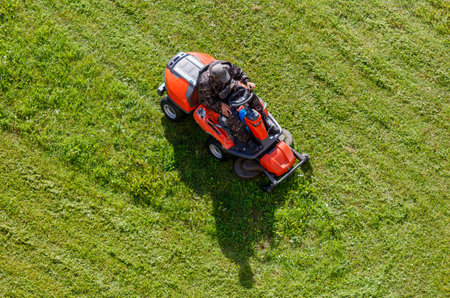A person operating a lawn mower in a park, cutting the grass.