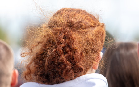 A woman with red hair has her hair in a messy bun. She is wearing a white hoodieの写真素材