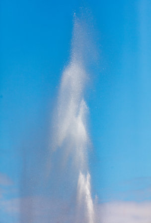 Water splashes from a fountain against a blue sky.の写真素材