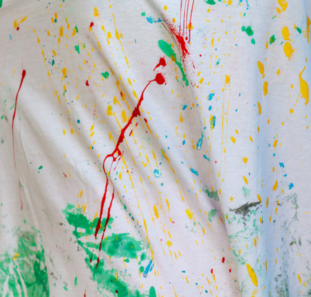 A shirt with splatters of paint on it. The splatters are in various colors, including red, yellow, and green. The shirt appears to be a work of art, with the splatters creating a sense of movementの写真素材
