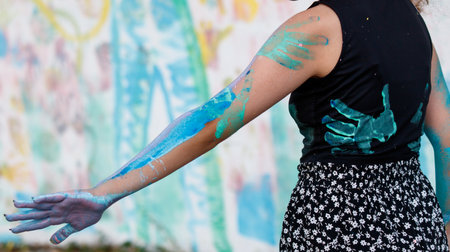 A woman with blue paint on her arm and hands. She is wearing a black shirt and black skirtの写真素材