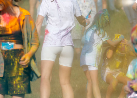 A group of people are running through a field of colorful paint. The scene is lively and energetic, as the people are enjoying themselves and participating in a fun activityの写真素材