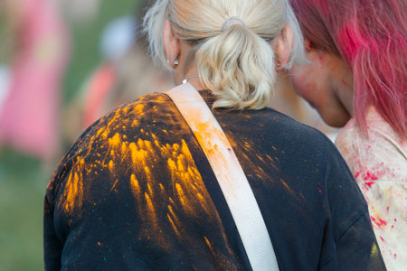 A woman with blonde hair is wearing a black shirt with yellow powder on it.の写真素材