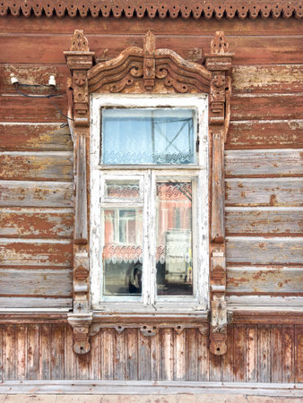 A window with a white curtain and a reflection of a person in the window. The window is old and has a wooden frameの写真素材