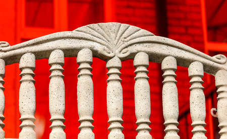 A white railing with red bricks in the background. The railing is made of cement and has a decorative designの写真素材