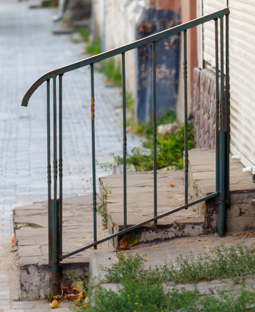 A rusted metal gate is leaning against a brick wall