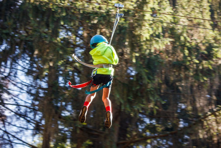 A boy bungee-sliding in the trees in summer.