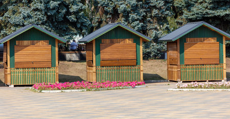 Three small wooden buildings with shutters and a flower garden in front of them. The shutters are open, and the flowers are pinkの写真素材