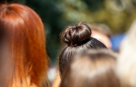 A woman with a bun on her head is in a group of people. The bun is pulled back and is visible on the top of her headの写真素材