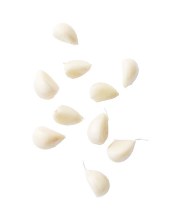 A close up of garlic cloves. The garlic cloves are sliced and scattered across the white background. Concept of freshness and naturalness, as the garlic cloves are a common ingredient in many dishesの写真素材