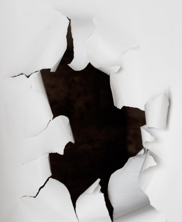 A white paper with a hole in it. The paper is in a dark room