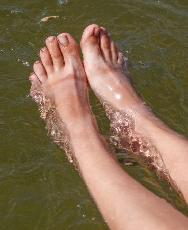 A person's feet are in the water, and the water is green