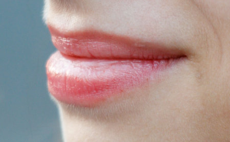 A woman's mouth is closed with a pink lip. The lips are slightly parted, and the woman's smile is visibleの写真素材