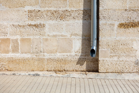 A metal pipe is sticking out of a brick wall. The pipe is bent and has a hole in itの写真素材