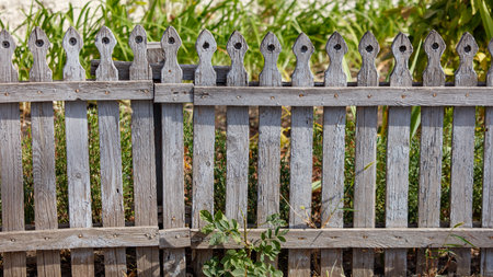 A wooden fence with a lot of holes in it. The fence is old and has a lot of rustの写真素材