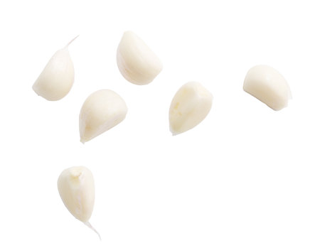 A close up of garlic cloves. The garlic cloves are sliced and scattered across the white background. Concept of freshness and naturalness, as the garlic cloves are a common ingredient in many dishesの写真素材