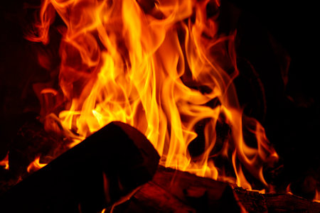 A log is burning in a fire, with the flames reaching up to the sky. Concept of warmth and comfort, as well as the natural beauty of a fireの写真素材