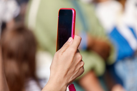 A person is holding a pink cell phone and taking a picture. Concept of modern technology and the...
