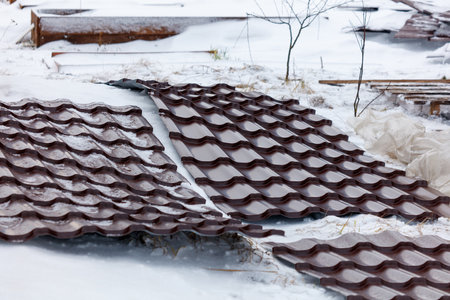 A roof is covered in snow and has a few missing shingles. The roof is brown and has a rustic appearanceの写真素材