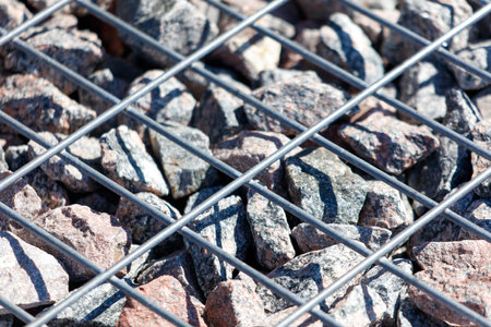 A close up of a rock field with a metal fence. The fence is made of metal and is placed on top of the rocks. The rocks are of different sizes and are scattered all over the fieldの写真素材