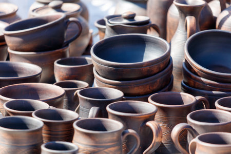 A collection of pottery, including bowls, cups, and vases, are displayed on a tableの写真素材