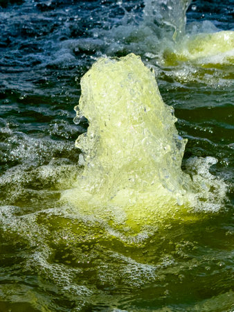 A large yellow bubble is rising from the water. The bubble is surrounded by a greenish-blue water