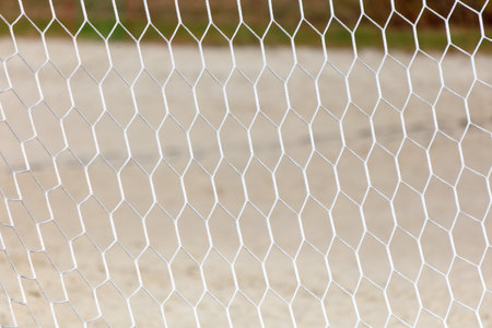 A white net with a pattern of squares and triangles. The net is on a sandy surface. The image has a calm and peaceful moodの写真素材