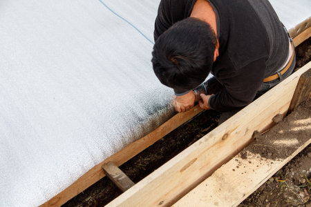 A man is working on a project, possibly laying down a new floor or repairing a damaged one. He is focused on his task and he is in a serious moodの写真素材