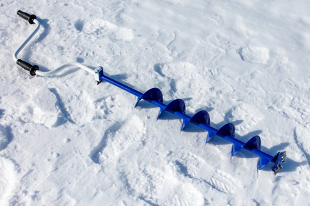 A blue and white snow tool with a handle and a blue handle. The tool is used for digging in the snowの写真素材