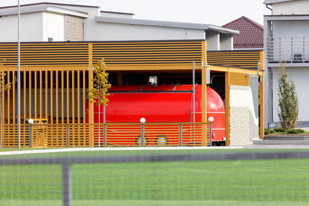 A red truck is parked in front of a building with a red roof. The truck is parked in front of a fence, and there is a bench nearby. The scene gives off a cozy and inviting atmosphereの写真素材