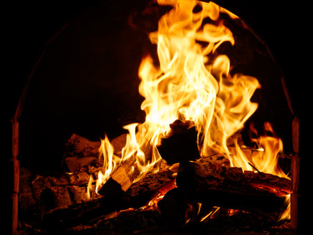 A close up of a fire with the flames reaching up to the top of the image. The fire is orange and yellow in colorの写真素材