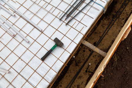 A hammer is resting on a piece of plywood with a wire sticking out of it. The wire appears to be used for securing the plywood to the groundの写真素材