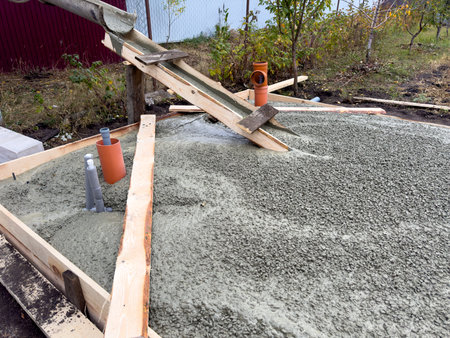 A cement mixer is pouring concrete into a hole in the ground. The cement is being poured into a wooden boxの写真素材