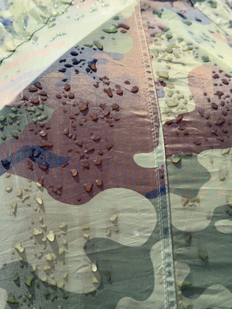 A camo jacket with water stains on it. The jacket is a camouflage pattern and has a brown and green color schemeの写真素材