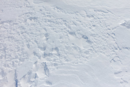 A snow covered ground with a few footprints. The snow is white and the ground is covered in it