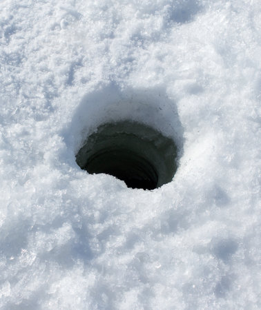 A hole in the snow is visible. The hole is small and he is in the middle of the snow. The snow is...