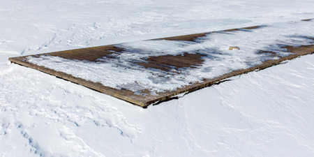 A long, narrow slab of concrete is covered in snow. The snow is white and fluffy, and it covers the...