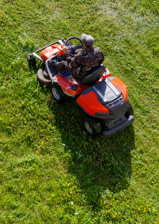 A person operating a lawn mower in a park, cutting the grass.