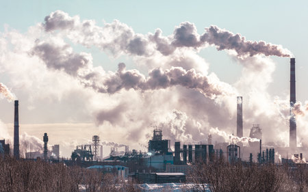 A city skyline with a lot of smoke coming out of the factories. The sky is hazy and the air is thick with pollutionの写真素材